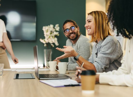 Business woman talking to her colleagues during a meeting in a boardroom. Group of happy business people working together in a creative office.